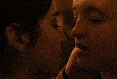 a close up of two women 's faces with one kissing the other