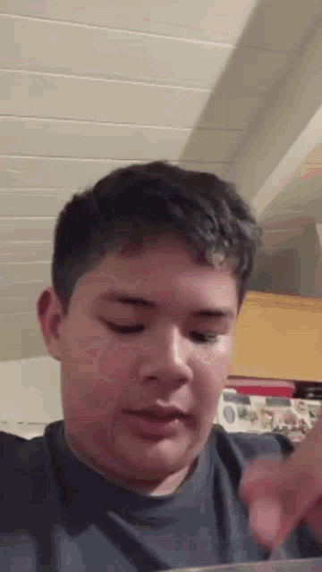 a young boy is making a funny face in a kitchen while looking at the camera .