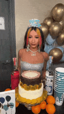 a woman wearing a tiara is standing next to a birthday cake .