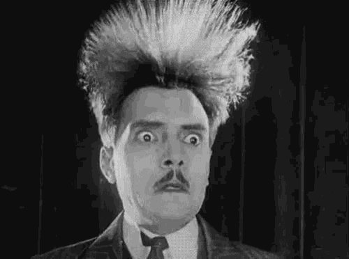 a black and white photo of a man with a moustache and a crazy hairdo .