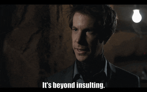 a man in a suit says " it 's beyond insulting " in a dark room