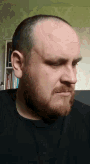 a man with a beard is wearing a black shirt and looking at the camera