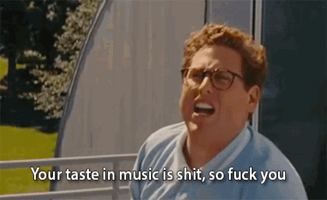 a man with glasses is screaming and saying your taste in music is shit so fuck you