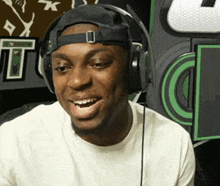 a man wearing headphones and a baseball cap smiles