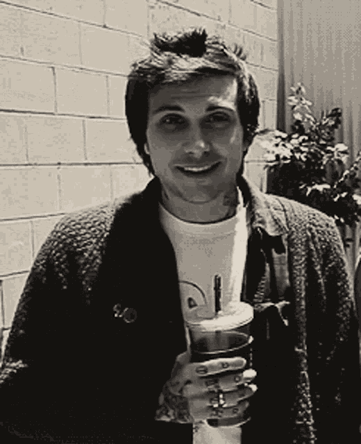a man with a tattoo on his arm holding a drink