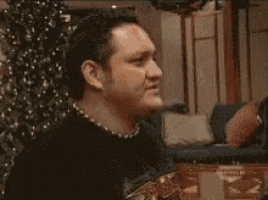 a group of people are sitting on a couch in a living room while a man holds a chair .