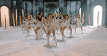 a group of women are dancing in a room with swords in the background