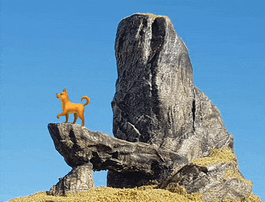 a toy dog standing on top of a rock