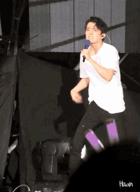 a man in a white shirt is singing into a blue microphone and the word flush is on the bottom