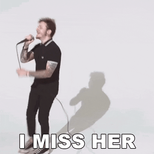 a man is singing into a microphone with the words `` i miss her '' written below him .
