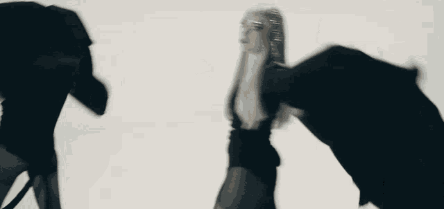 a woman in a black dress is holding a black object in her hand