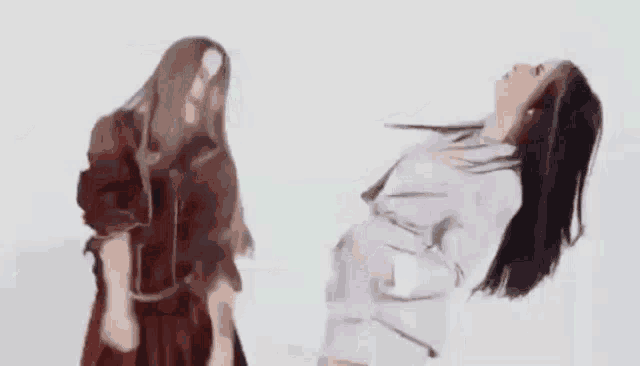 two women are dancing together in a white room .
