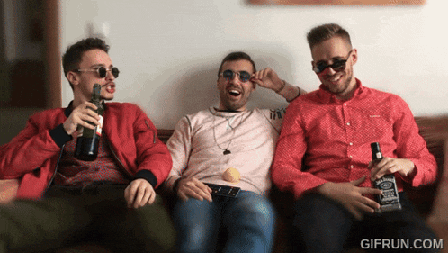 three men are sitting on a couch holding bottles of jack daniels whiskey