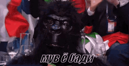 a black gorilla is sitting in front of a table with glasses and a sign that says myb e badi