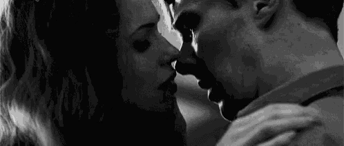 a black and white photo of a man and a woman kissing .