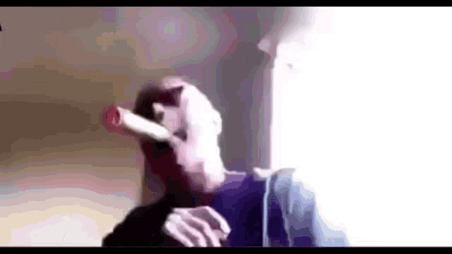 a man is smoking a cigarette in a room with a bottle in his mouth .