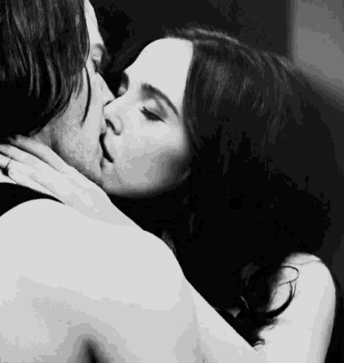a black and white photo of a man and woman kissing each other .