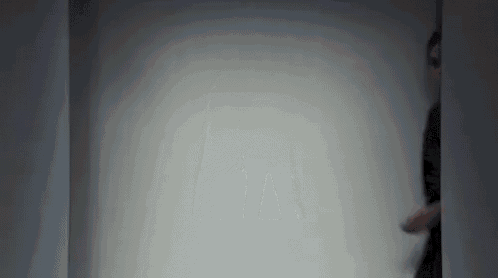 a man is walking through a doorway in a dark room with a white wall .