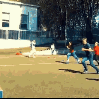 a group of people are running on a field in front of a white building
