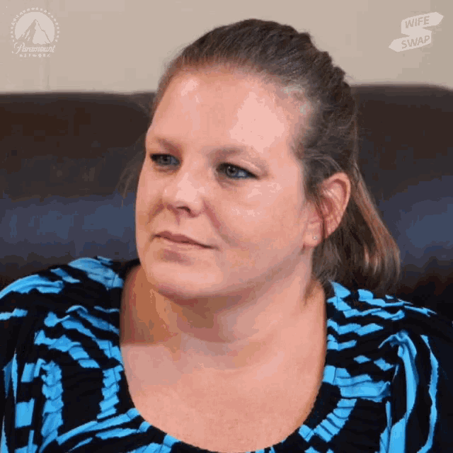 a woman is sitting on a couch with a paramount sign in the background
