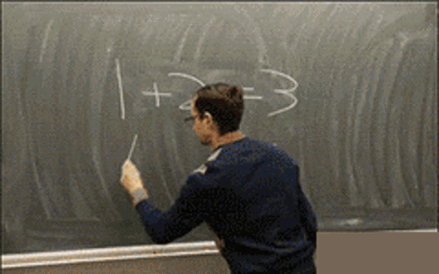 a man is writing on a blackboard with 1 + 2 = 3 written in white chalk