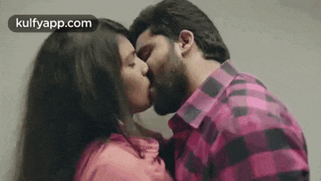 a man and a woman are kissing in front of a wall .