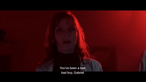 a woman is standing in a dark room and talking to a boy .