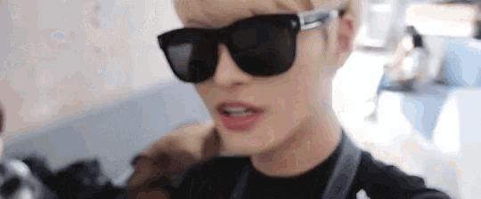 a man wearing sunglasses and a black shirt looks at the camera