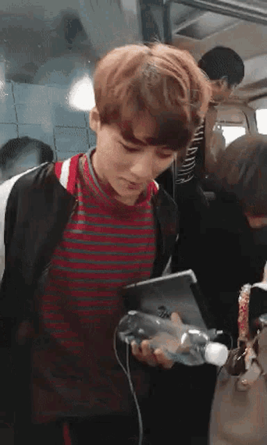 a man in a striped shirt is holding a cell phone in his hand