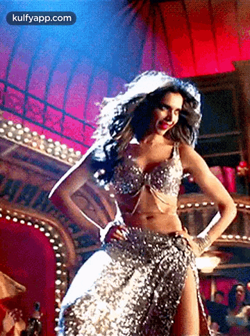 a woman in a sequined dress is dancing in front of a red curtain .
