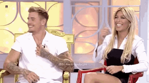 a man and a woman are sitting next to each other on a chair and smiling .