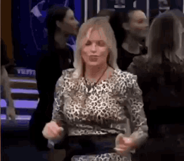 a woman in a leopard print shirt is dancing in front of a crowd of people .