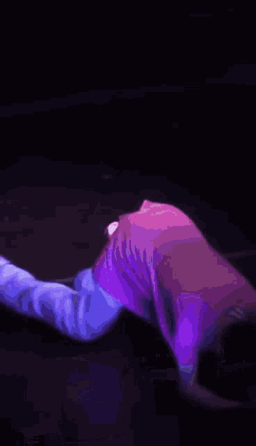 a man in a pink shirt and white pants is kneeling on a stage