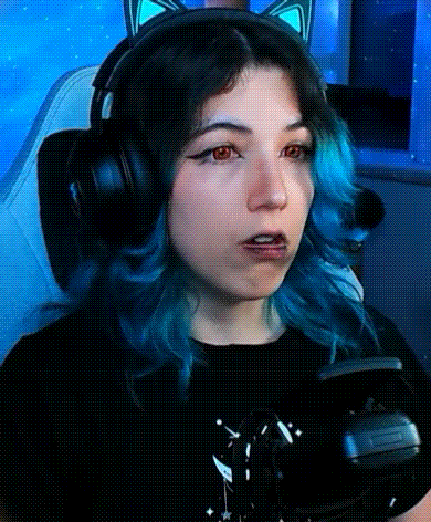 a girl with blue hair and headphones is sitting in a chair .
