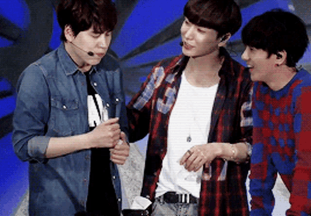three young men are standing next to each other and one of them is wearing a plaid shirt