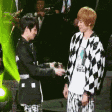 a man wearing a white shirt that says ' a.r.g. ' on it is shaking hands with another man