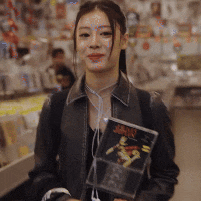 a woman in a leather jacket holds a cd case that says ' heavy ' on it