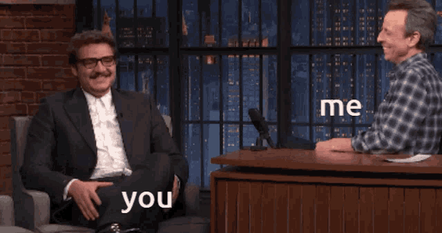 two men are sitting at a table and one of them says you