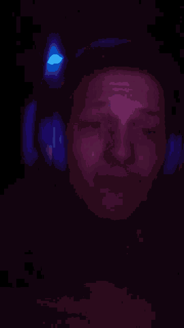 a man wearing headphones in a dark room with a blue light behind him