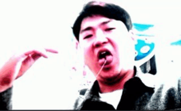 a man is sticking his tongue out while holding something in his mouth .