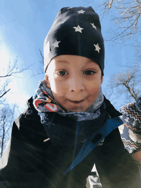 a young boy wearing a black jacket and a hat with white stars