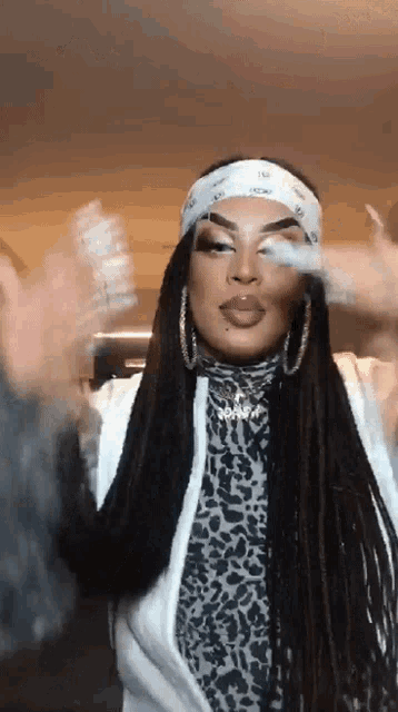 a woman with dreadlocks is wearing a bandana and a leopard print top .