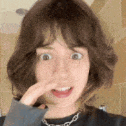 a woman is covering her nose with her hand .