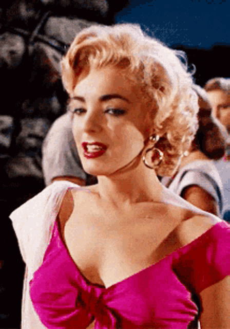 a woman in a pink top is standing in front of a group of people