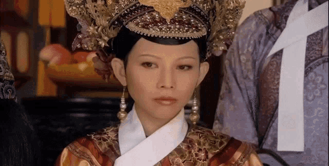 a woman wearing a crown and earrings is looking at the camera .