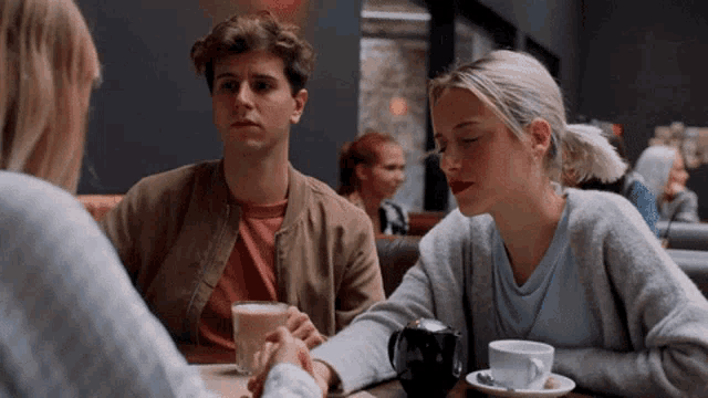 a man and a woman are sitting at a table with a cup of coffee