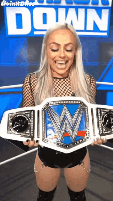 a woman is holding a wrestling championship belt in front of a down sign