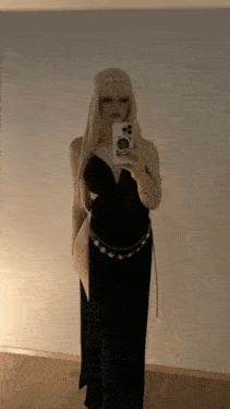 a woman in a black dress is taking a selfie