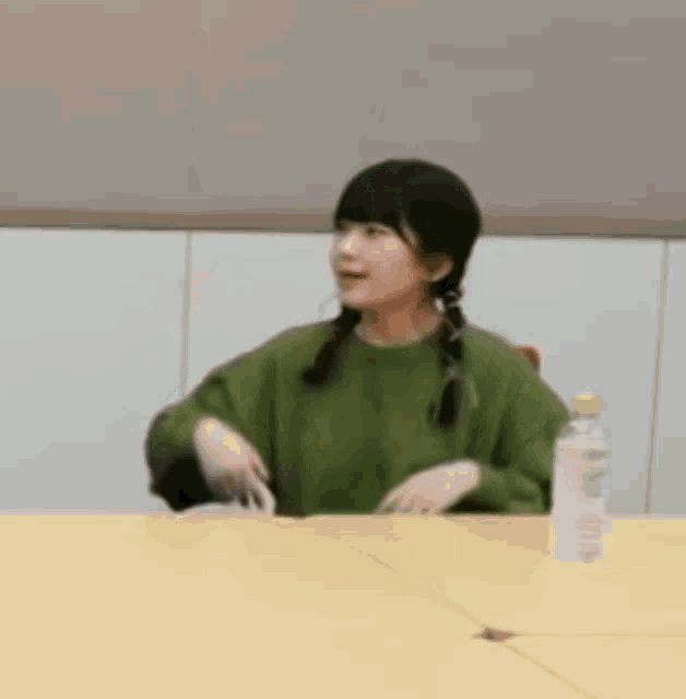 a woman is sitting at a table with a bottle of water in front of her .