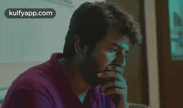 a man is sitting at a table with his hands on his chin .